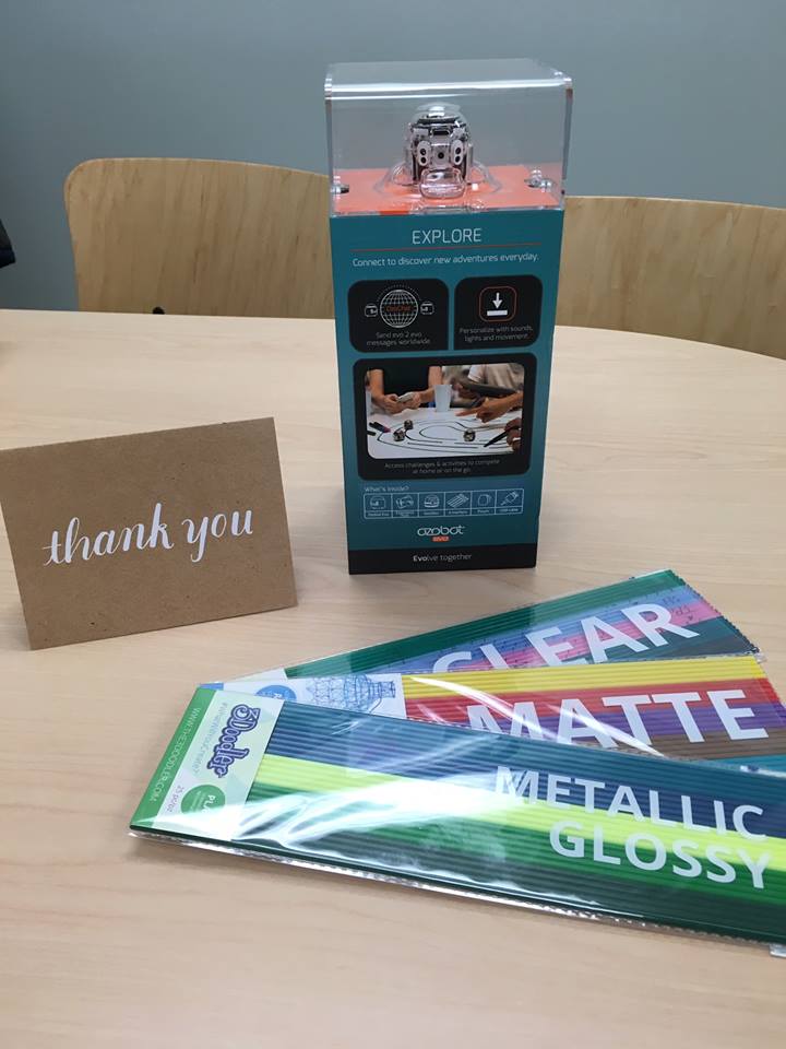 a librarian displaying an ozobot evo robot and 3D printing filaments next to a thank you card