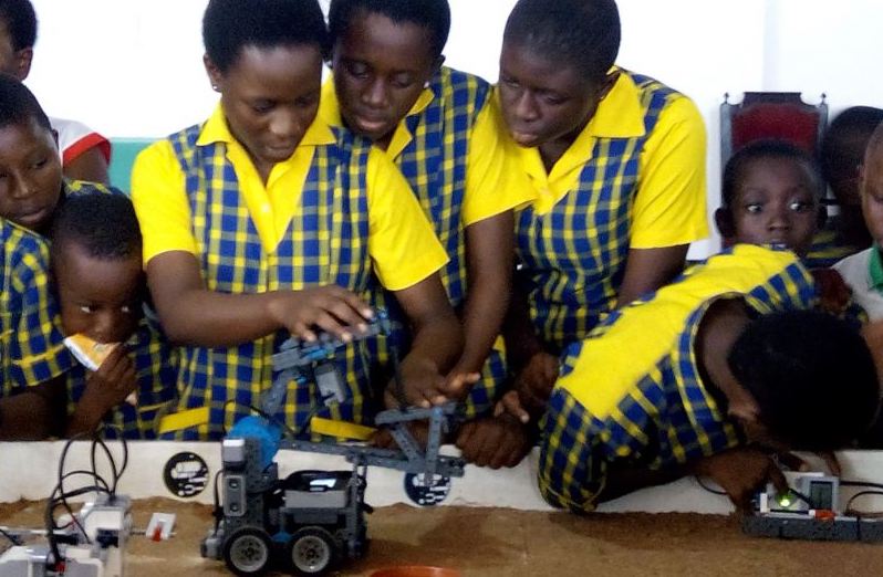 students in school uniforms working with robots in the classroom