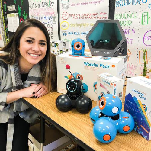 a teacher posing with the dash and cue coding robots from wonder workshop