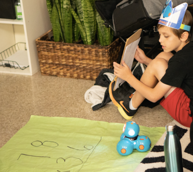 an elementary school student coding with the wonder workshop dash robot