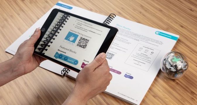 a person holding a tablet while coding with the sphero bolt robot