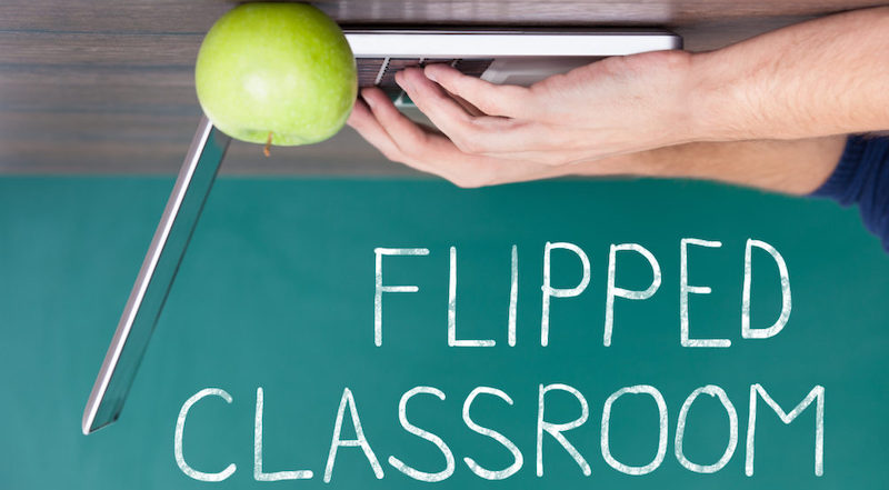 a computer and an apple upside down to represent a flipped classroom