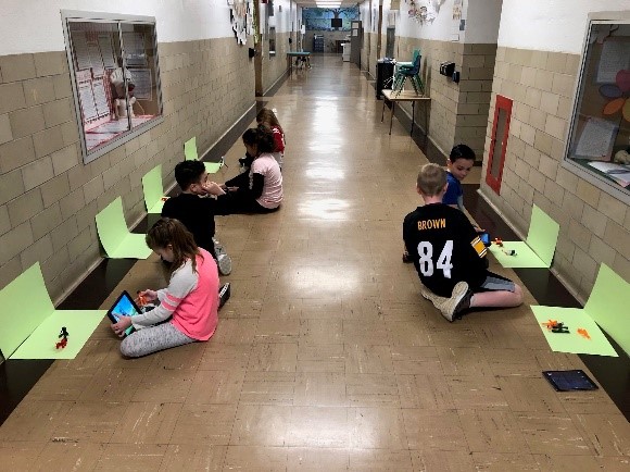 students working on a robotics project in an elementary school hallway