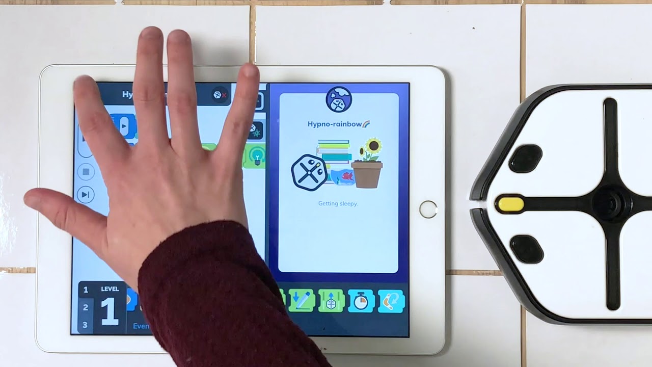 a student holding his hand over a tablet while coding with the Root Robot