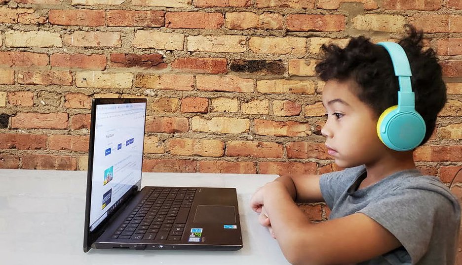 a student sitting at a table with headphones on doing a digital lesson