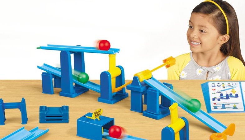 an early education student watches as balls travel through a maze she engineered