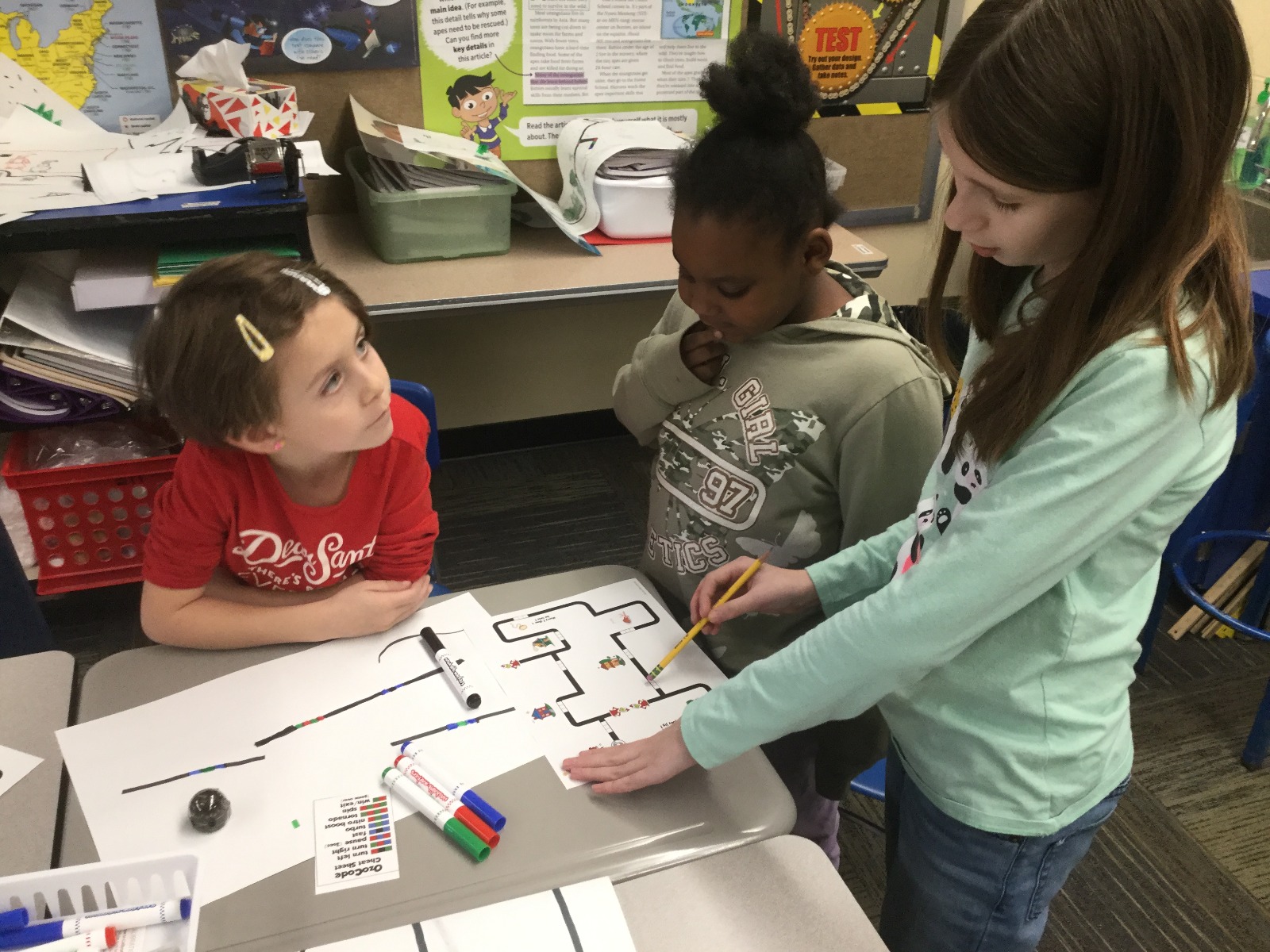 students color coding with the ozobot robot in the classroom as an educator looks on