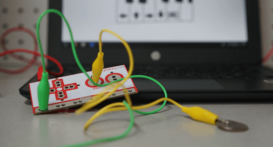 the makey makey board connected to a computer with alligator clips