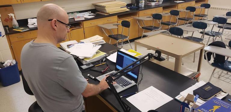 a teacher in an empty classroom teaching remotely