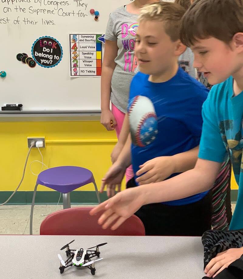 students learning to pilot a drone in a coding education class by programming it