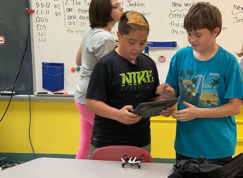 students programming a parrot drone in the classroom