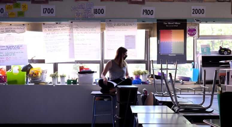 a special education teacher looks at an empty classroom while teaching students with learning differences remotely
