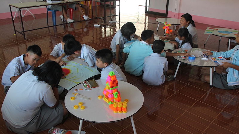 students sitting on the floor and using tables to work together in a PBL school