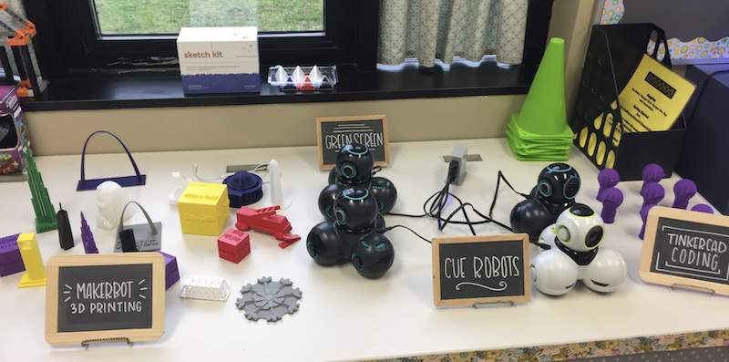 a table set up to display educator tools include 3D printed objects, the wonder workshop cue robot, and Tinkercad creations
