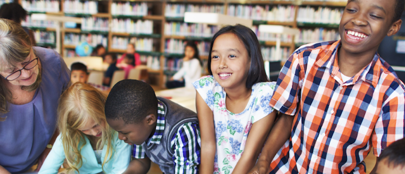 a group of diverse students learning together with a culturally responsive teacher in a school library