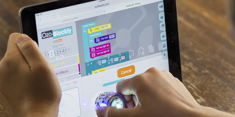 a student holding an ozobot evo robot to the OzoBlockly coding environment while practicing Blockly programming