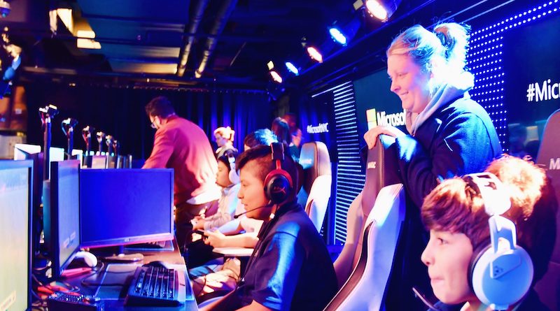 young students participating in an esports tournament while a coach watches