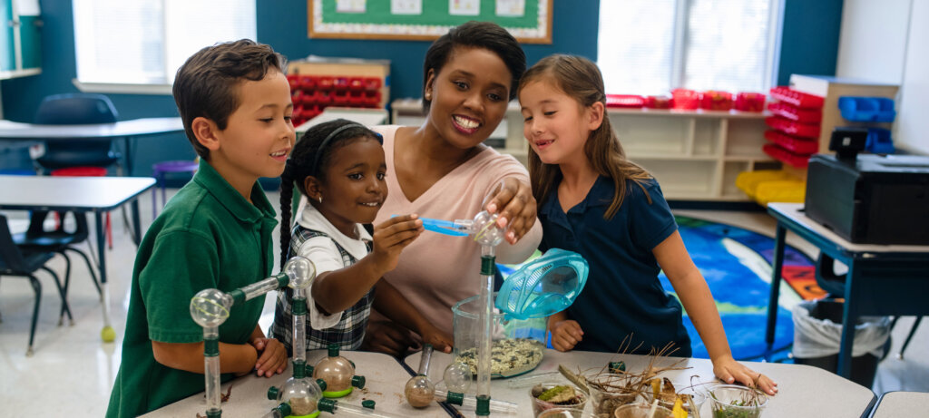 a classroom teacher works with students on a hands-on experiment in a STEM program