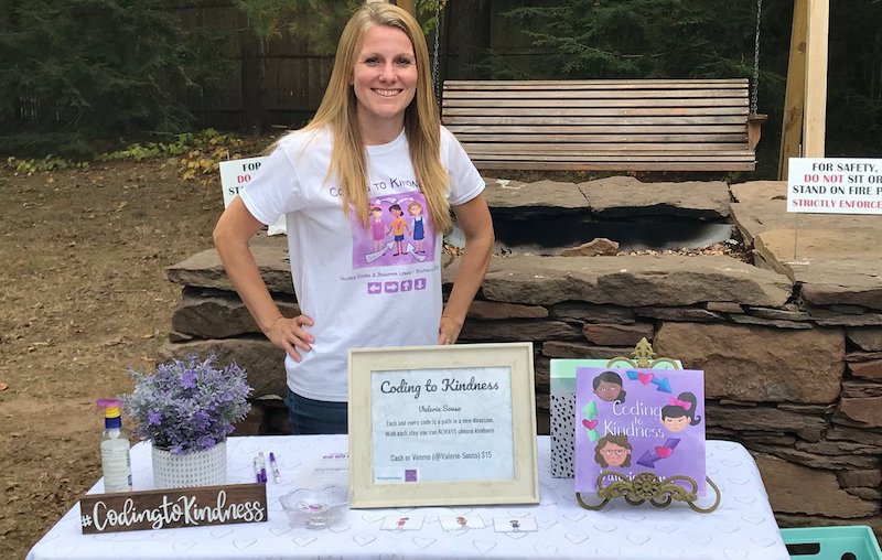 stem teacher valerie sousa poses with her coding to kindness book behind a table