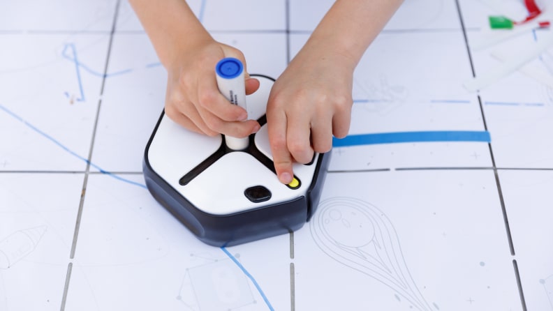 a student using the root coding robot with a blue marker in its slot after receiving it through a grant program 