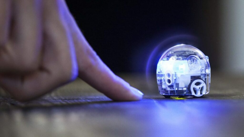 a person holding their finger next to the illuminated ozobot evo robot