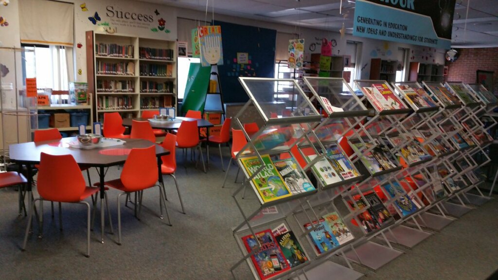 an elementary makerspace set up in the school library with tables, chairs, and books for students