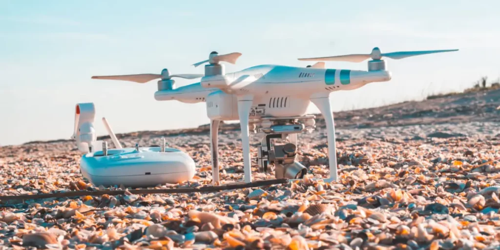 a drone sitting on the ground with a controller at its side