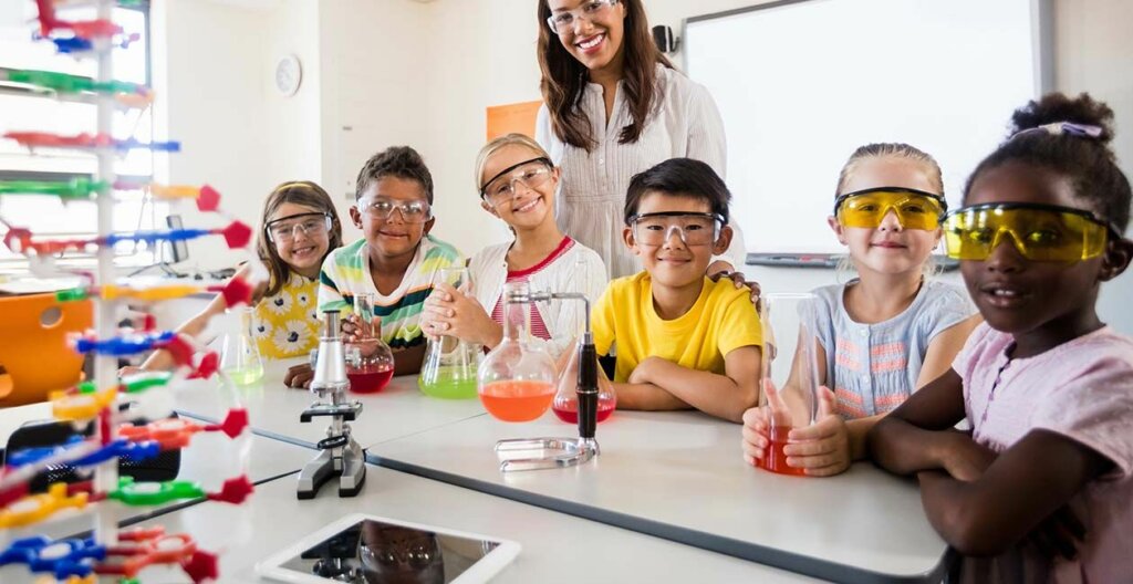young students sitting with a teacher while conducting an afterschool STEM experiment