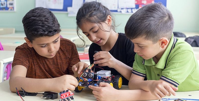a group of students in a stem education class working on building a robot