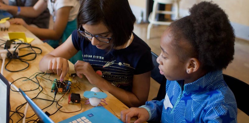 two students building a hummingbird robot project and coding on the computer