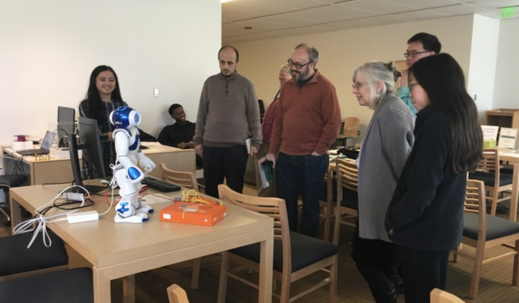 a group of educators watching a robot stand on a table