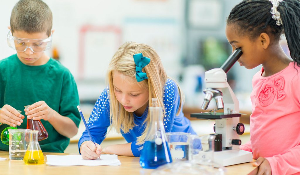 students conducting STEM experiments with a microscope and beakers in early education