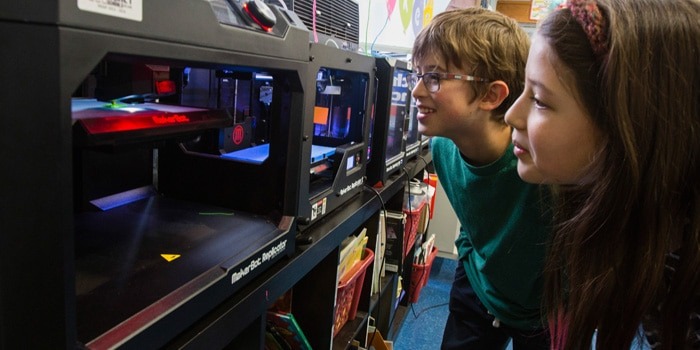 students watching a project form on a 3D printer in their school