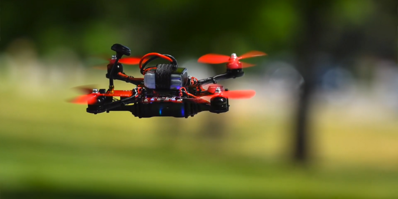 the RubiQ coding drone hovering over some grass