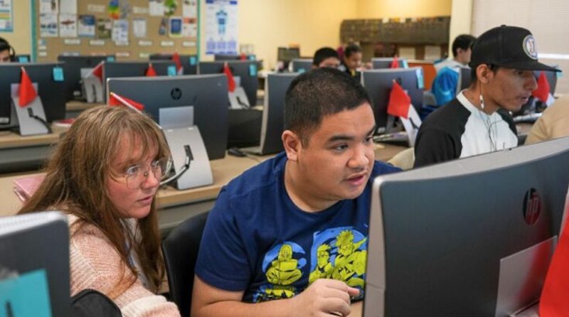 a school technology coach helping a student with an assignment on the computer